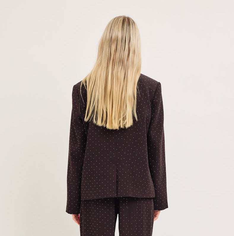 Person wearing a brown suit standing against a white background