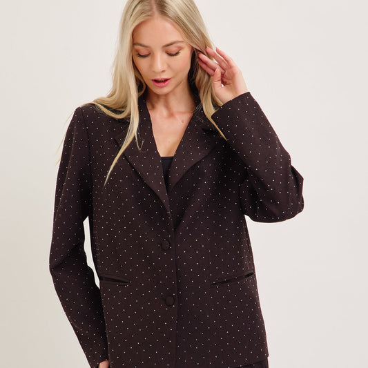 Woman wearing a dark polka dot suit on a plain background