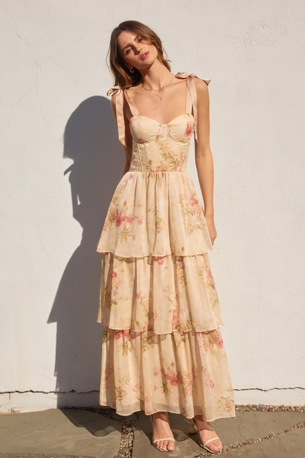 Woman wearing a floral tiered dress against a white wall