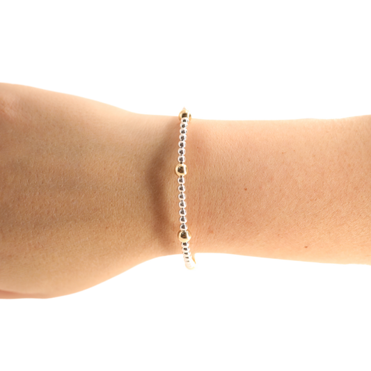 Gold bracelet on a wrist against a white background