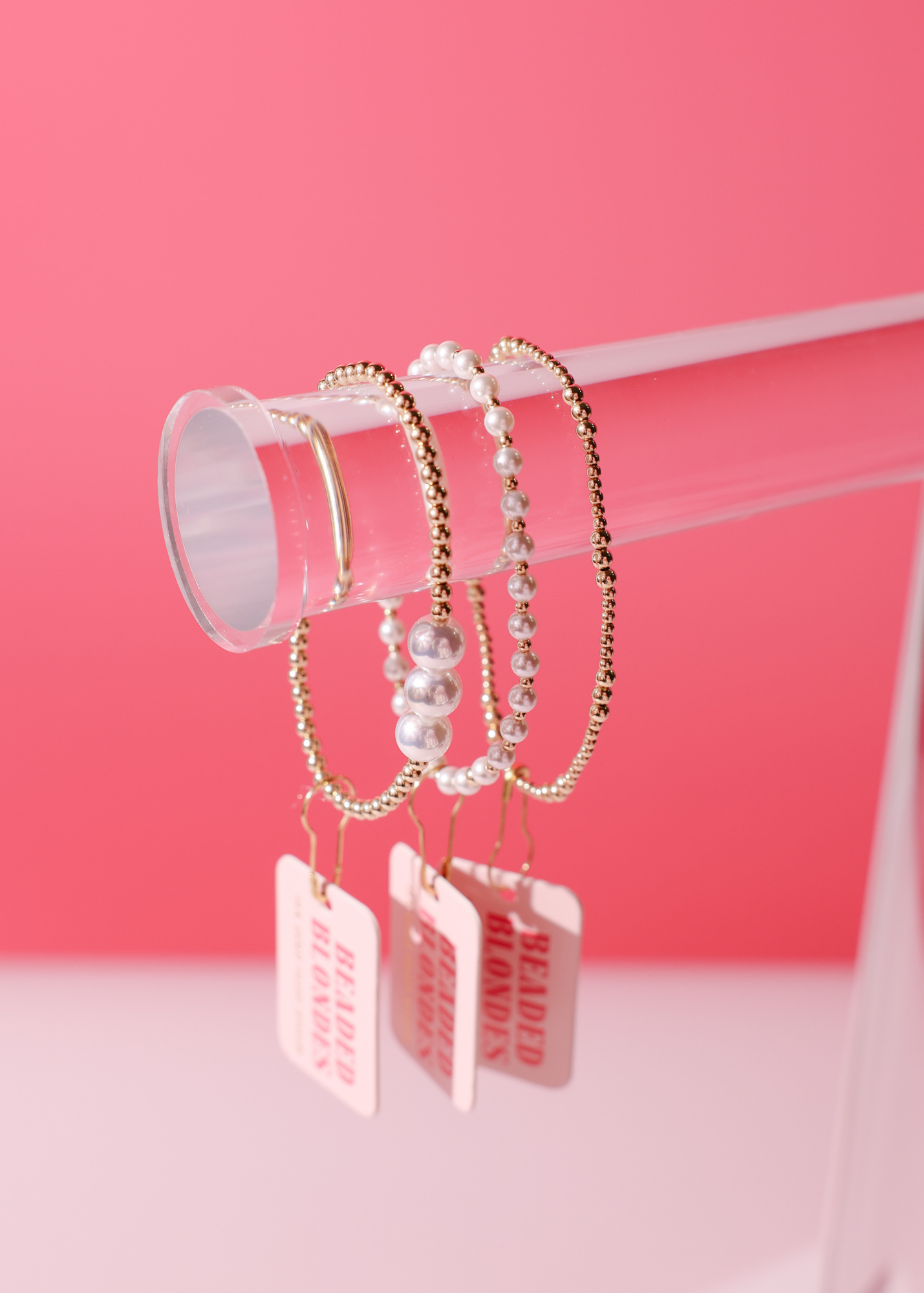 Set of bracelets with tags on a pink background