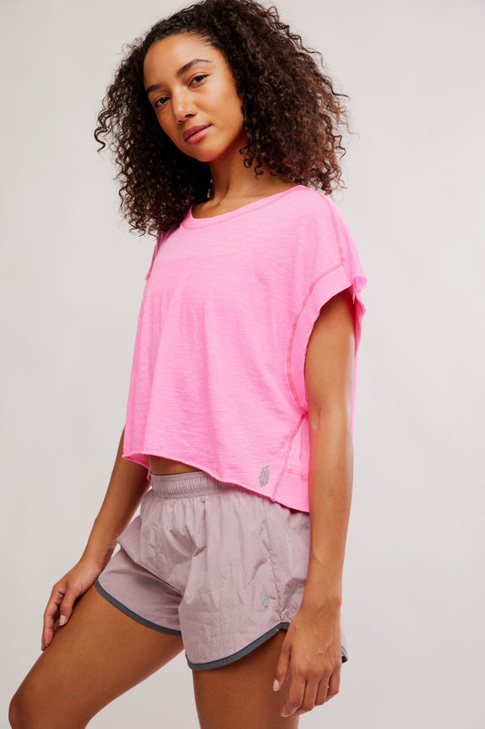 model wearing pink shirt with mauve shorts on a white background standing to the side