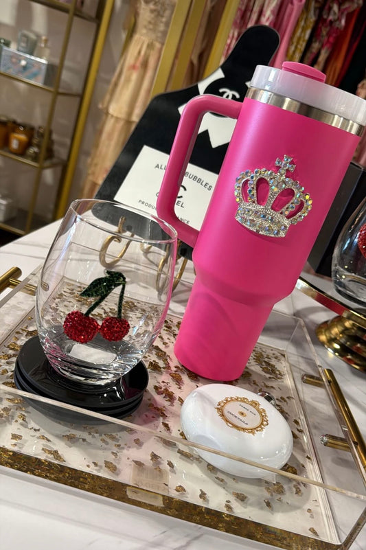 Pink tumbler with decorative elements on a reflective surface