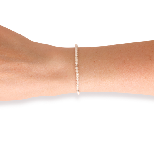 A delicate single-strand pearl bracelet with a silver-toned setting, shown worn on a person's wrist against a plain white background.