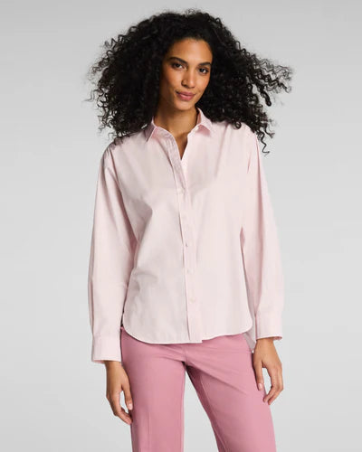 Woman wearing a light pink SPANX shirt and pink pants against a gray background