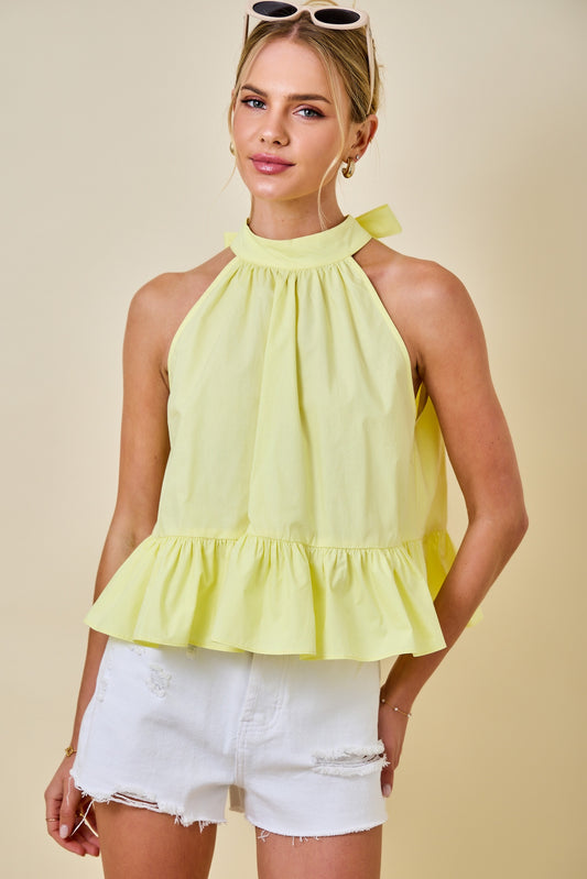 Woman wearing a yellow top and white shorts against a beige background