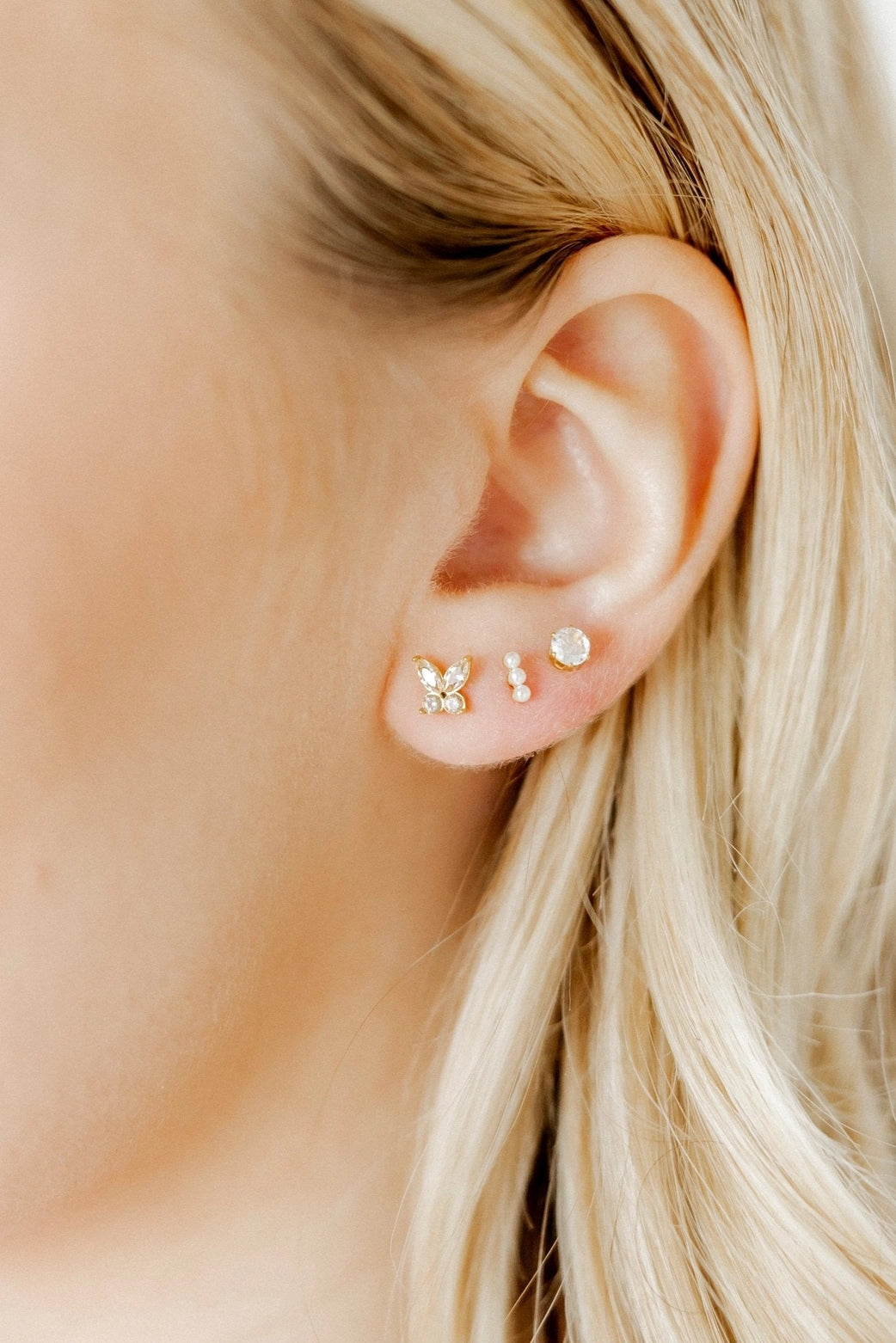 Close-up of an ear wearing gold earrings with a blurred background