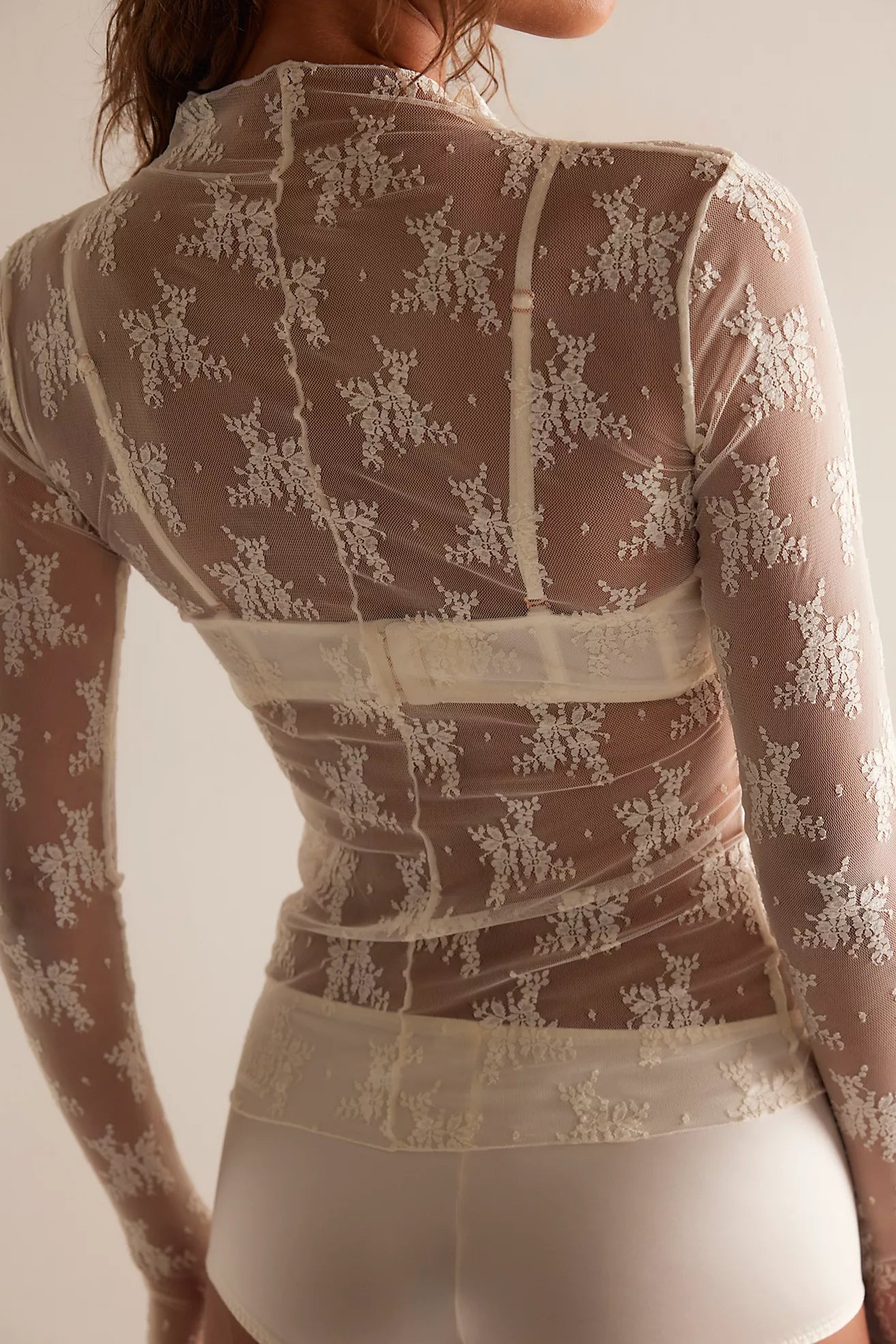 Sheer lace top with long sleeves on a plain background
