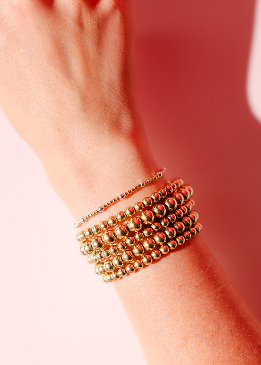 Gold bracelets on a wrist with a blurred background