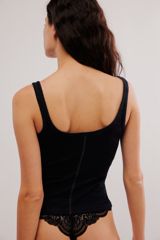 Person wearing a black bodysuit with lace details on a plain background