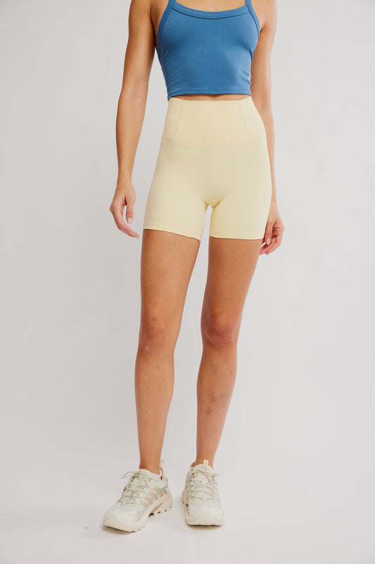 Person wearing a blue sports bra and yellow shorts on a plain background