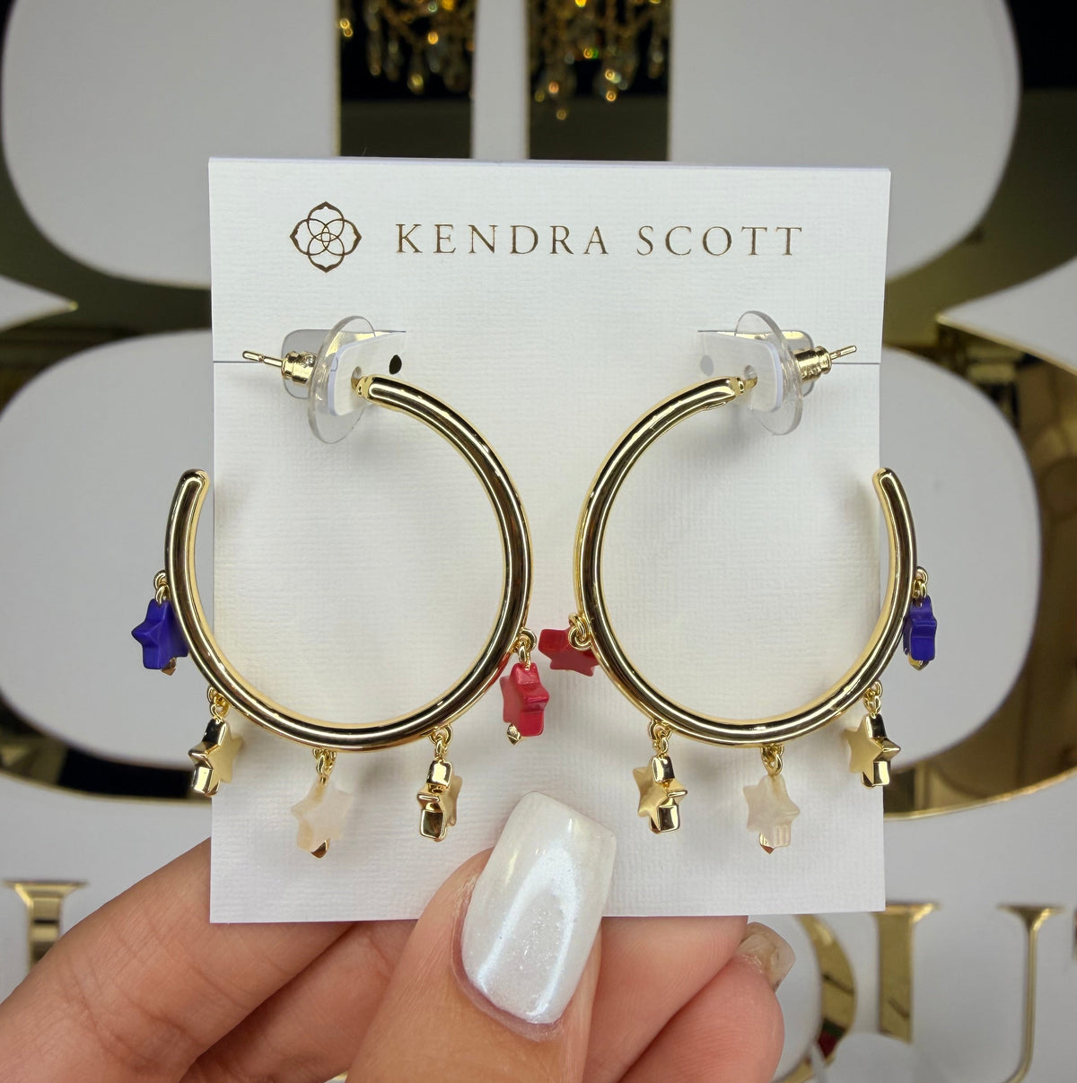 Gold hoop earrings on a Kendra Scott card held by a hand.