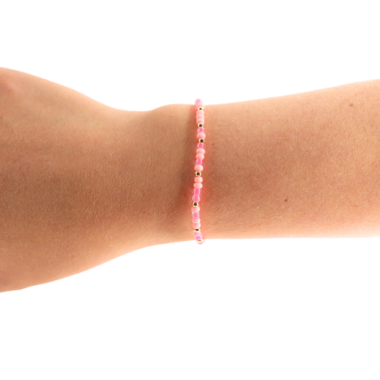 Pink beaded bracelet on a wrist against a white background