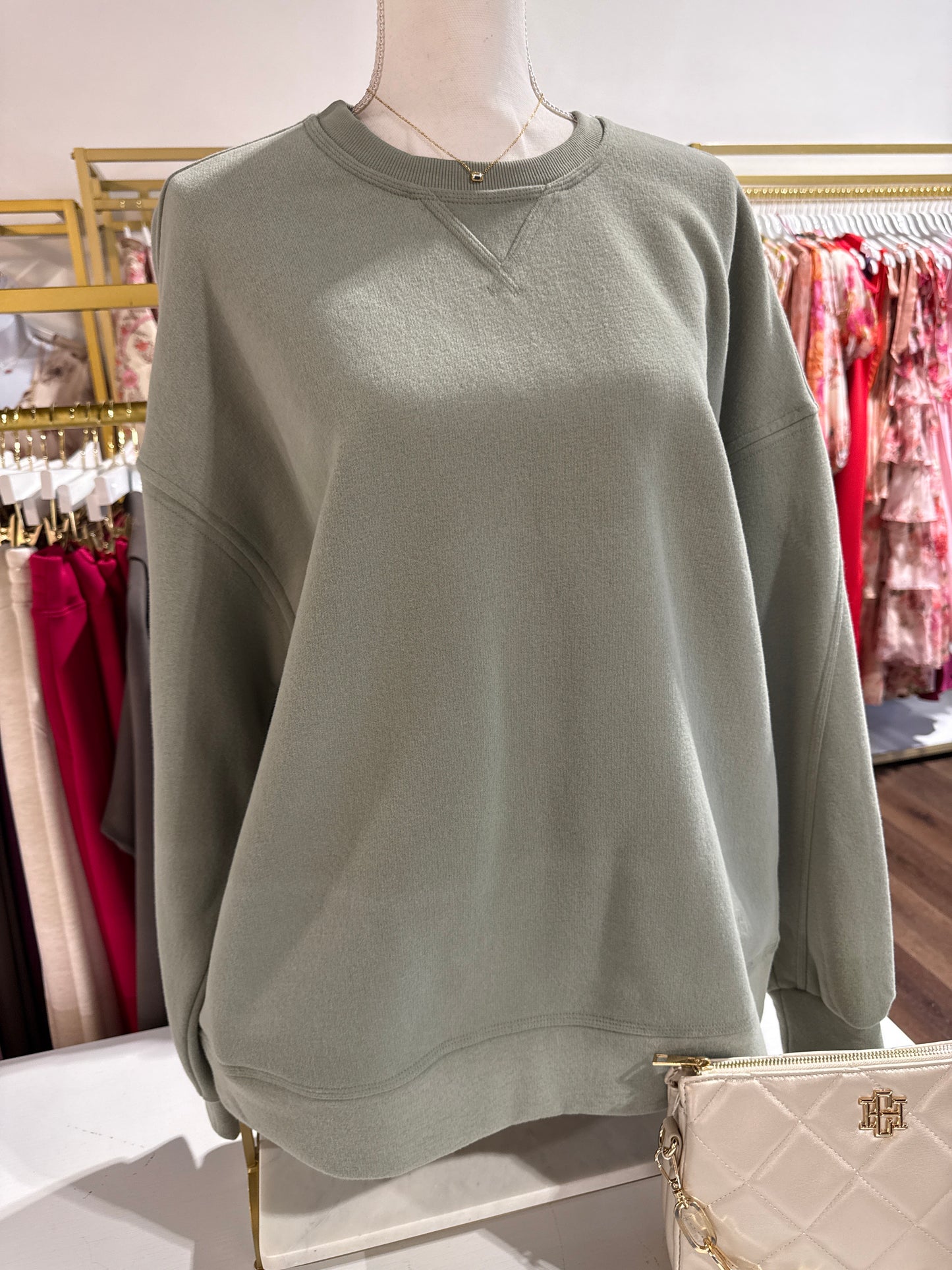 Green sleeveless top on a mannequin with a blurred store background