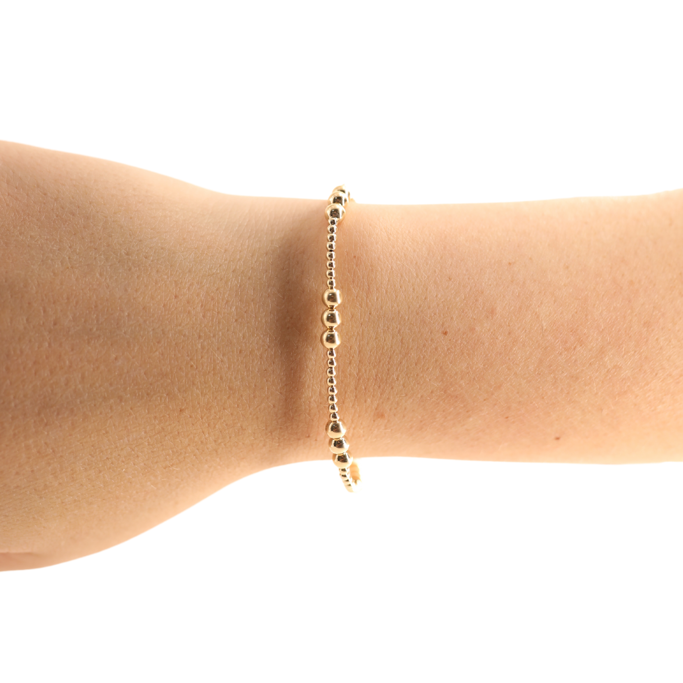 Gold bracelet on a person's wrist against a white background