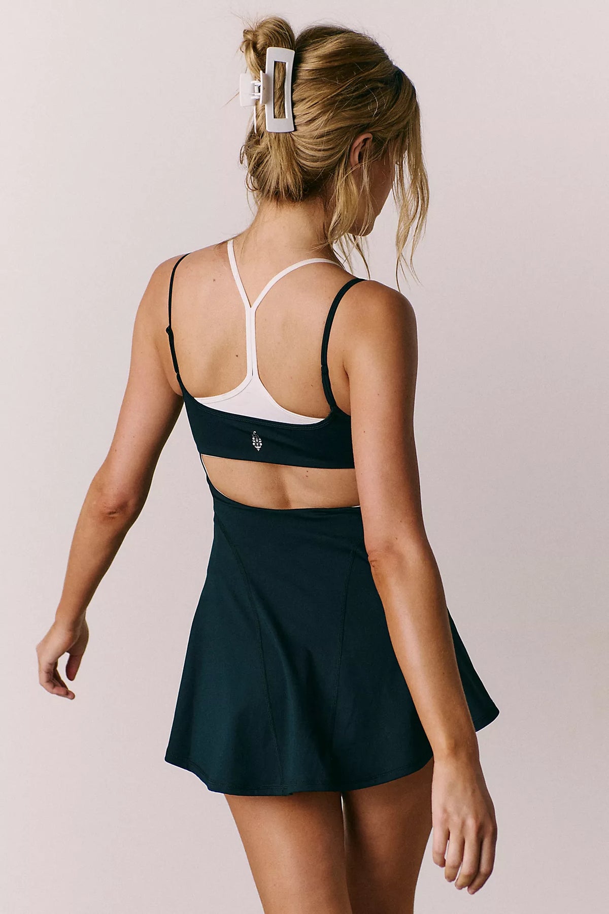 Woman wearing a black sports bra and skirt on a plain background