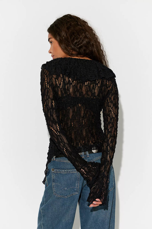 Person wearing a black lace top and blue jeans against a white background