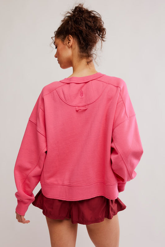 Person wearing a pink oversized hoodie and maroon shorts on a light gray background