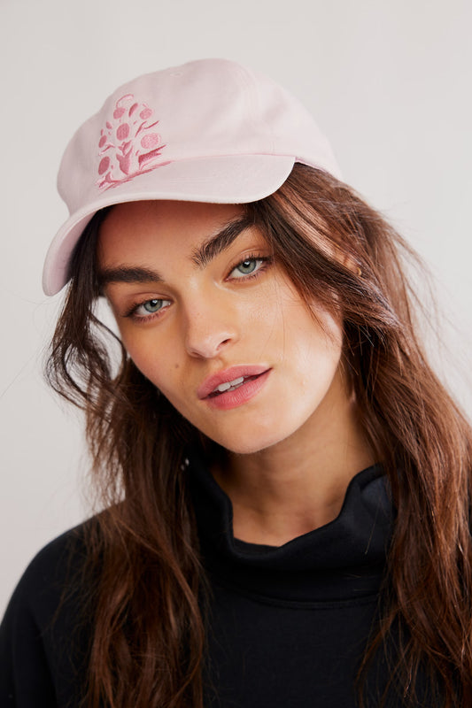 Woman wearing a pink cap with a floral design on a plain background