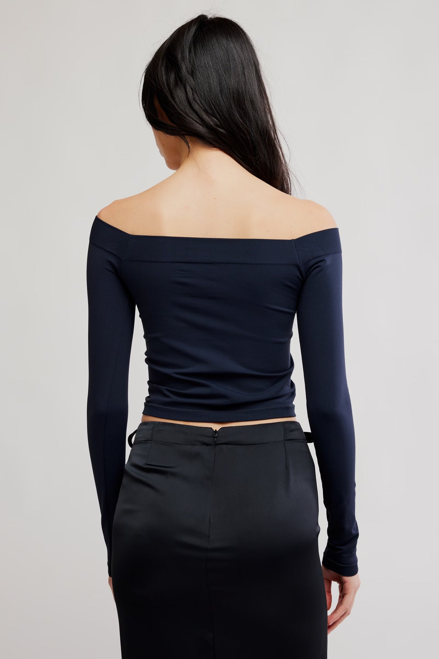 Model wearing black off the shoulder top facing backwards