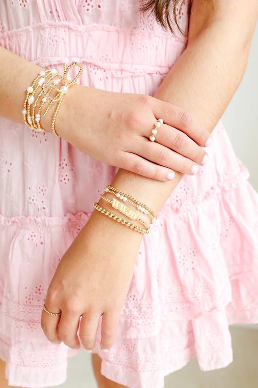 Beaded Blondes pearl rings and gold bracelet stacks styled with a pink ruffled dress.