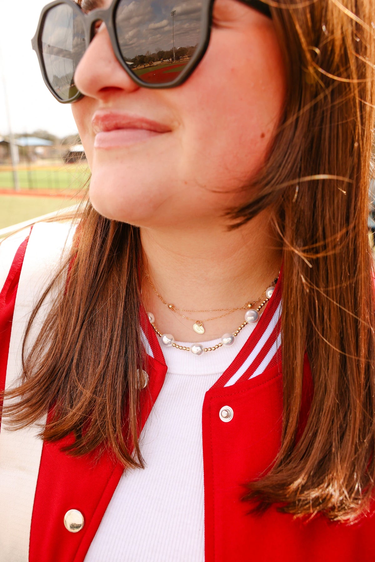 Model wearing a gold logo charm necklace.