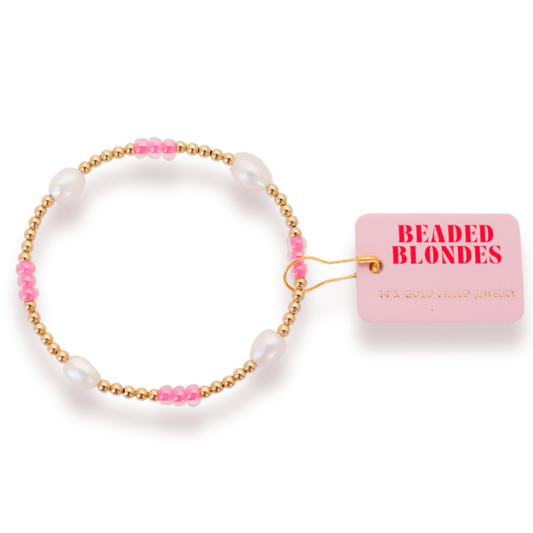 Beaded Blondes Hot Pink Pearl Poppi Bracelet with white pearls, pink accents and gold beads beside a brand tag.