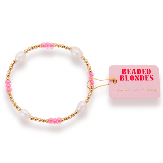 Beaded Blondes Hot Pink Pearl Poppi Bracelet with white pearls, pink accents and gold beads beside a brand tag.
