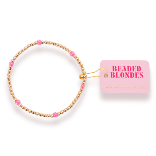 Beaded Blondes Hot Pink Poppi Bracelet with hot pink glass accents and gold beads beside a pink brand tag.