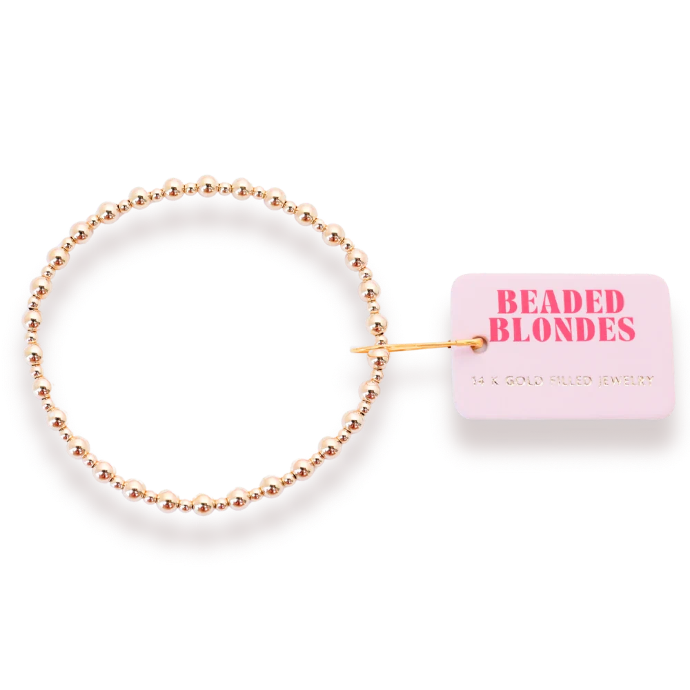 Beaded Blondes Katy Mini Bracelet in Gold beside a pink jewelry tag.