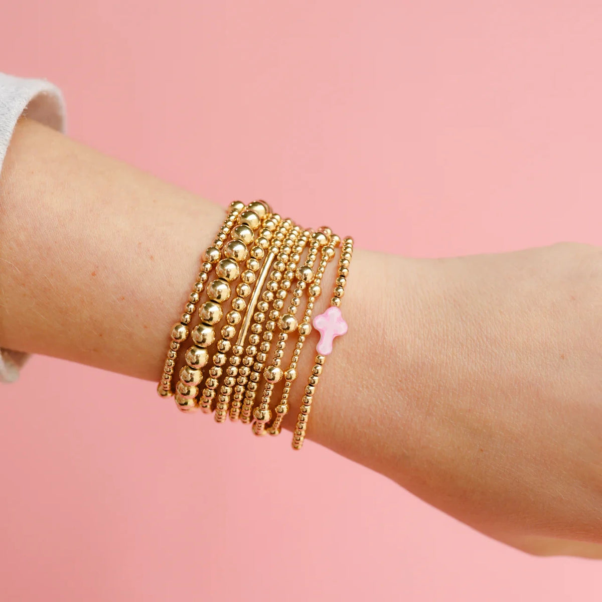 Layered gold bracelets worn together on a wrist.