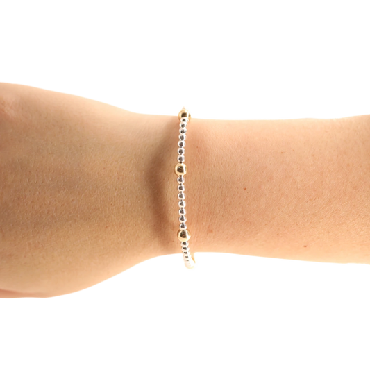 Silver and gold Olive beaded bracelet worn alone on a wrist.