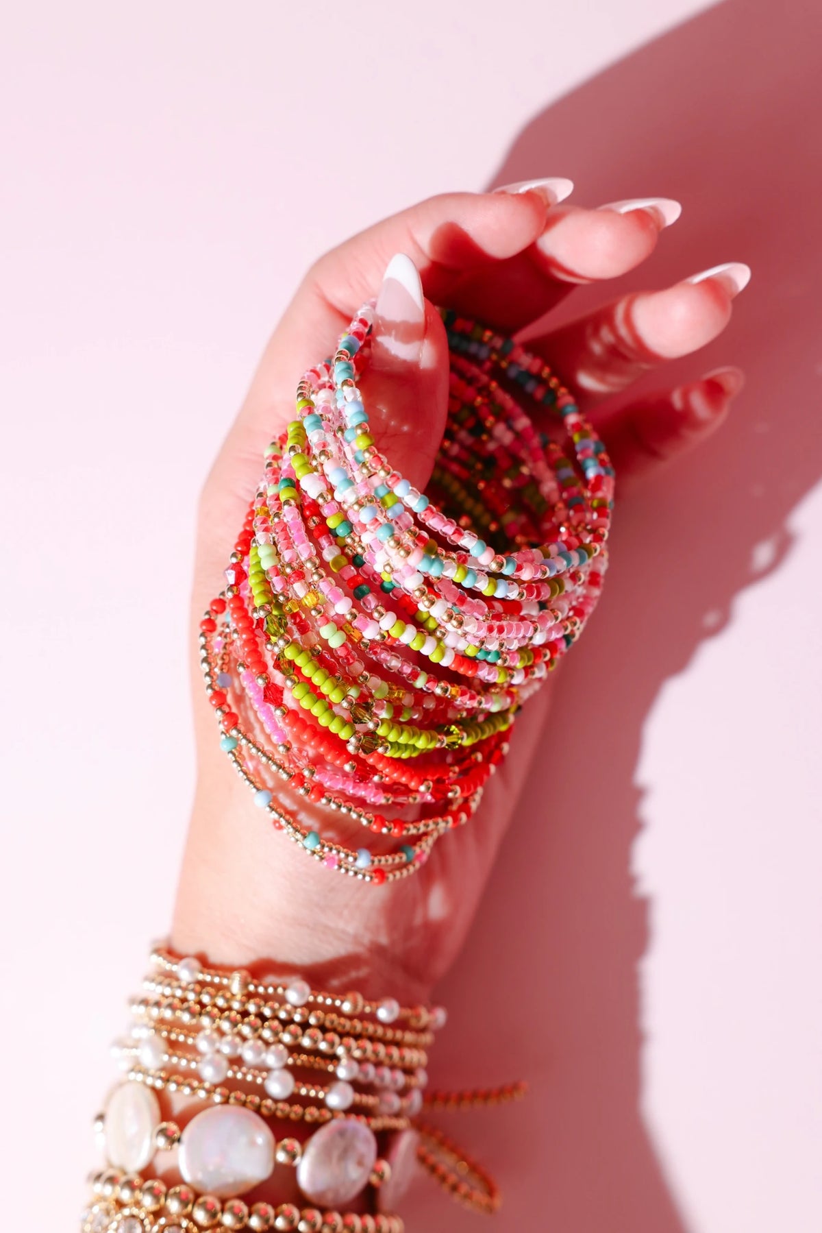 Hand holding several colorful beaded bracelets with jewelry tags.