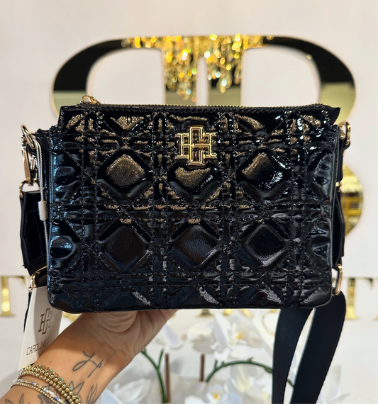 Black textured handbag with gold accents held by a person against a blurred background