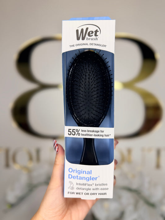 Wet Brush Original Detangler packaging held by a hand with a blurred background