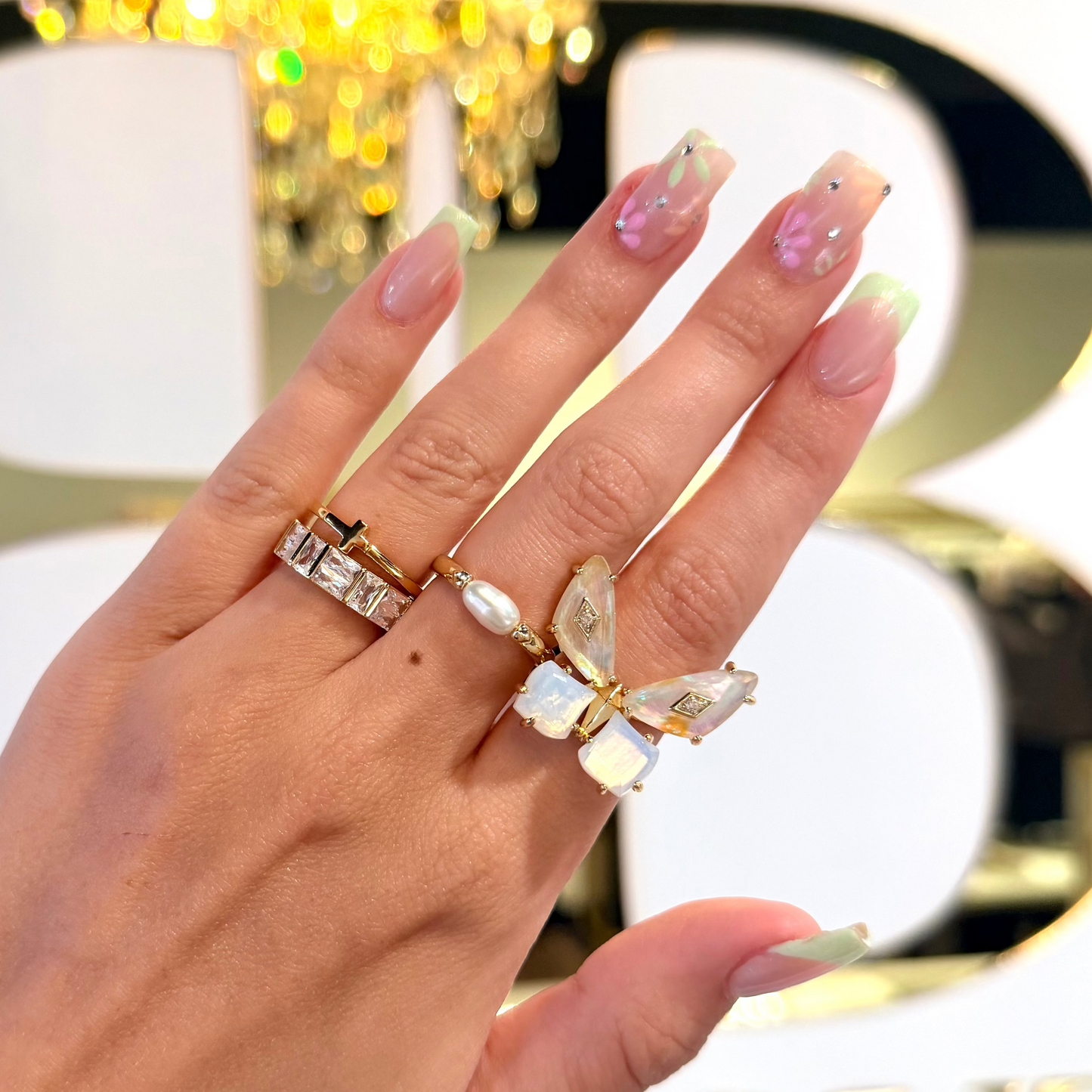 Hand infront of BB with gold Kendra Scott rings
