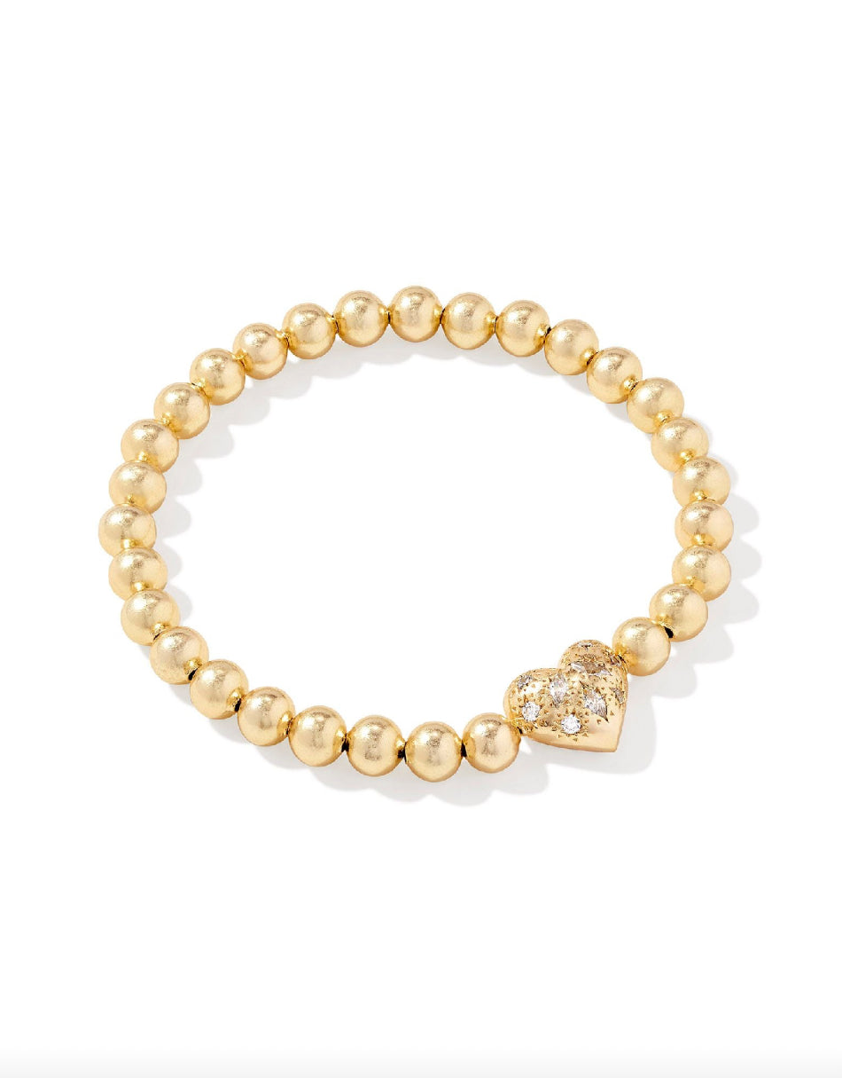 Gold Kendra Scott beaded bracelet with a heart-shaped pedant on a white background