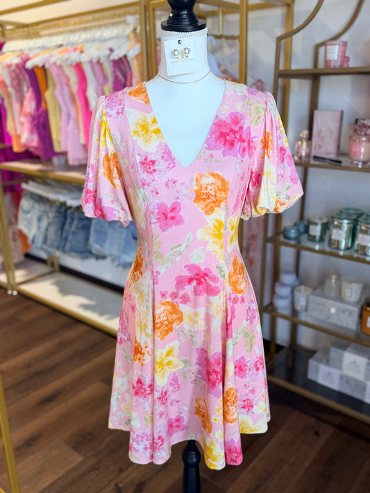 Floral dress on a mannequin in a store setting with shelves in the background