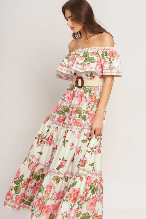 Woman wearing a floral off-shoulder dress with a belt on a plain background