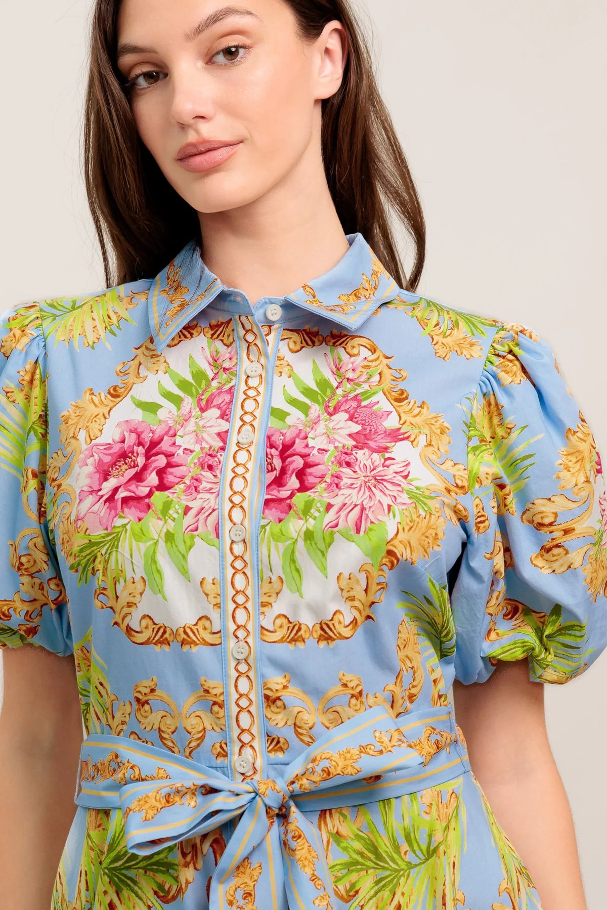 Woman wearing a floral and baroque patterned blouse against a plain background