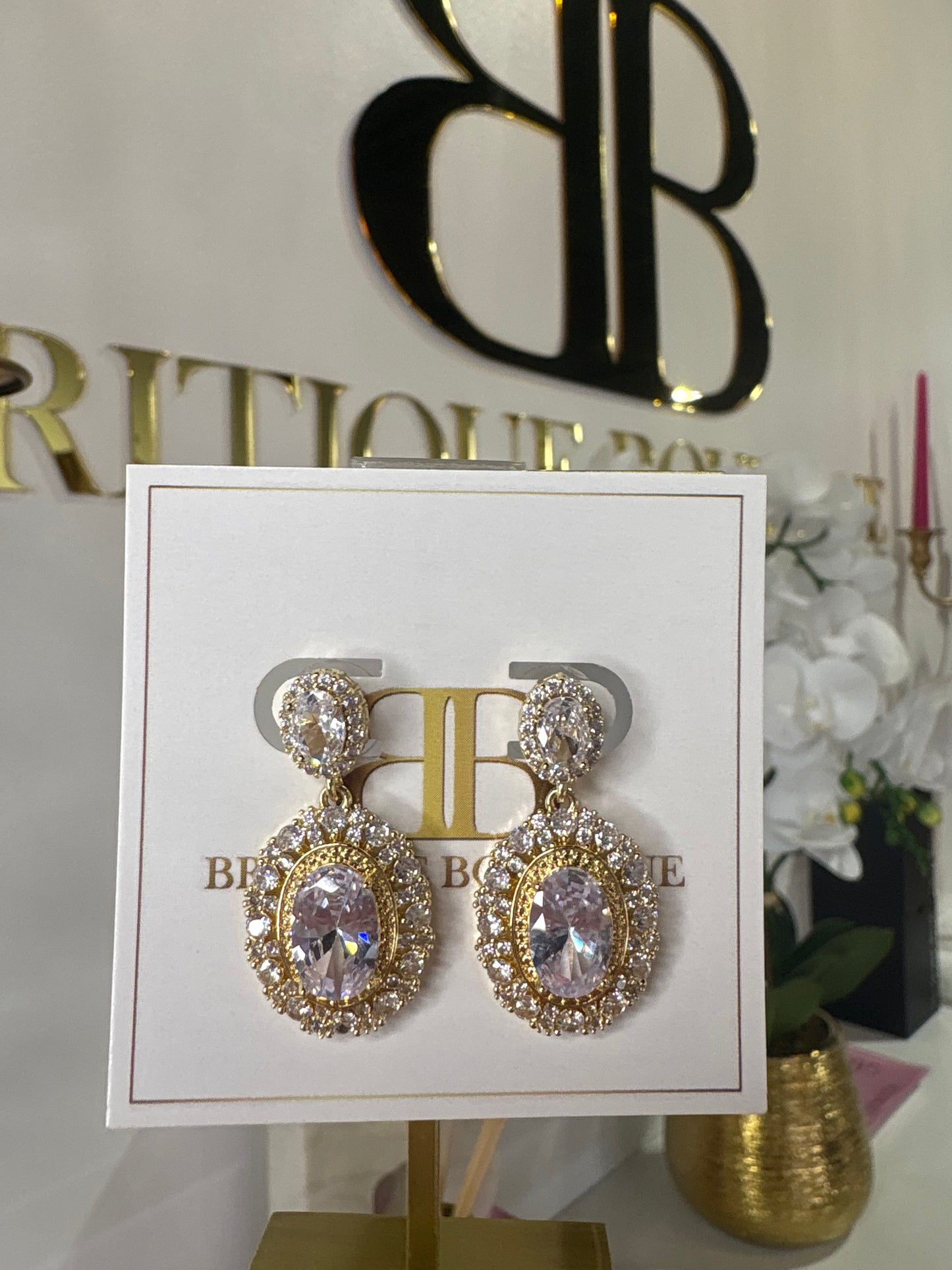 Gold and crystal earrings on a branded card with a decorative background