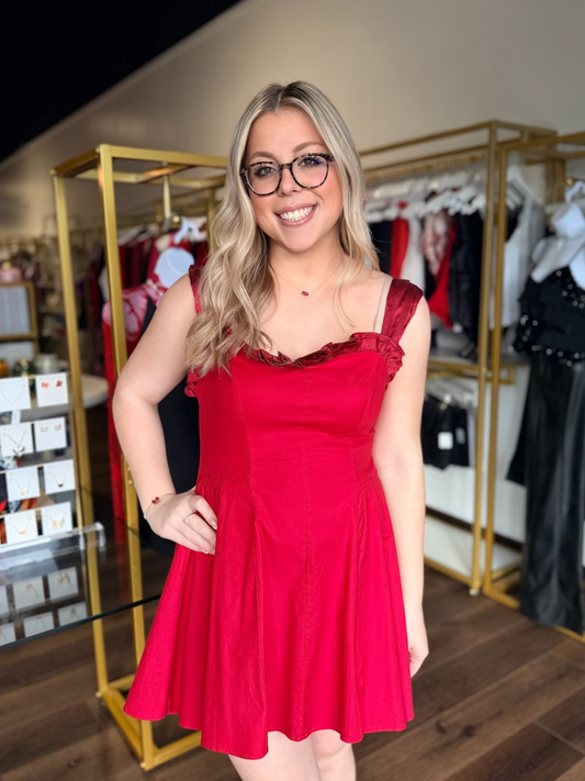 Woman in a red dress standing in a clothing store.