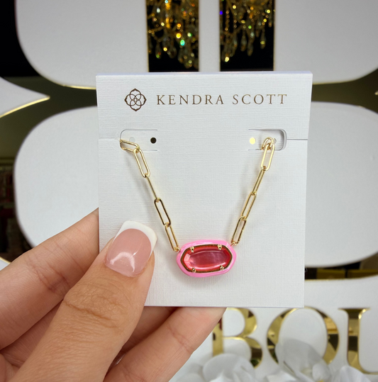Kendra Scott earring on a card held by a hand with a blurred background
