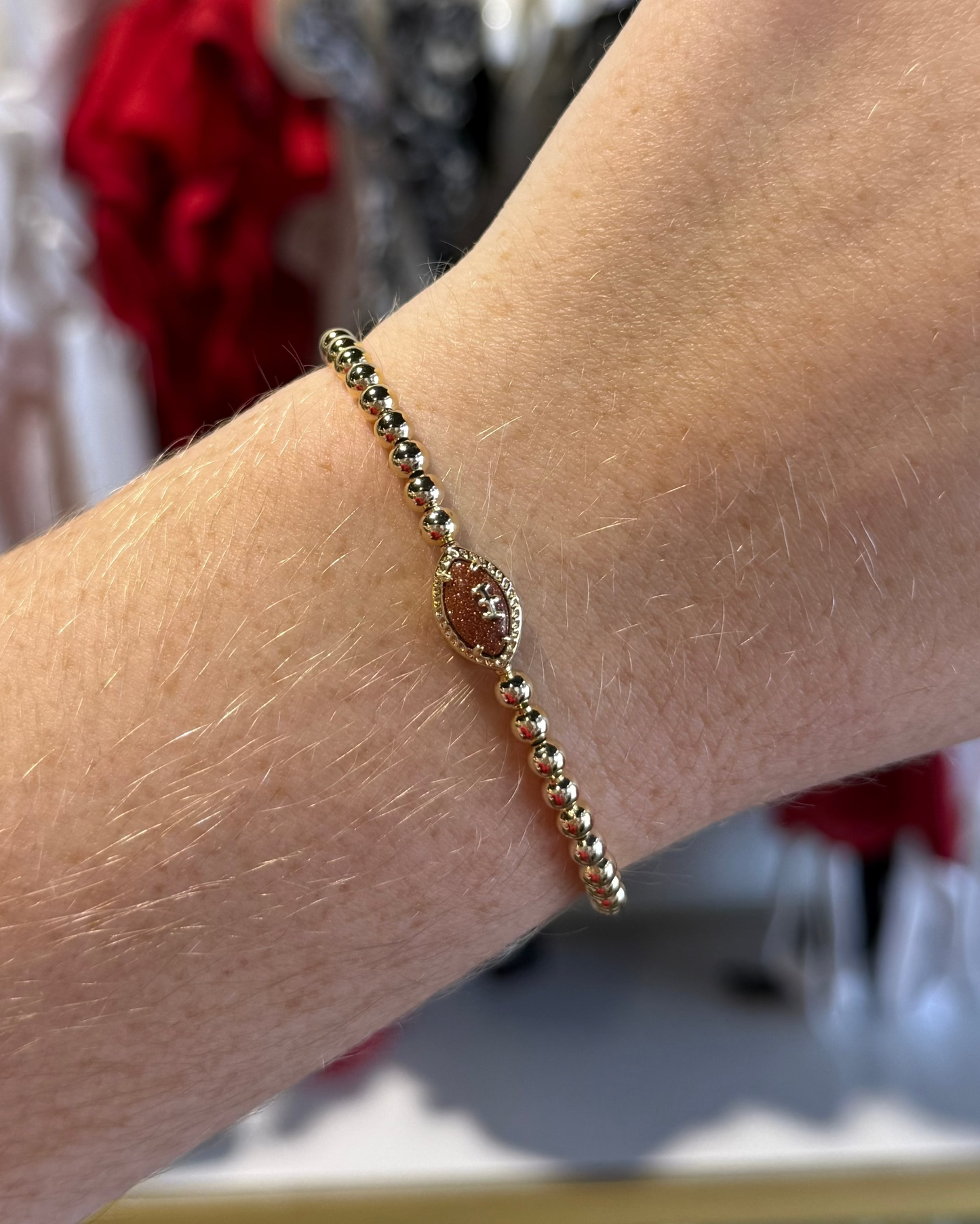BOUTIQUE KENDRA SCOTT FOOTBALL GOLD STRETCH BRACELET IN ORANGE GOLSTONE ON ARM