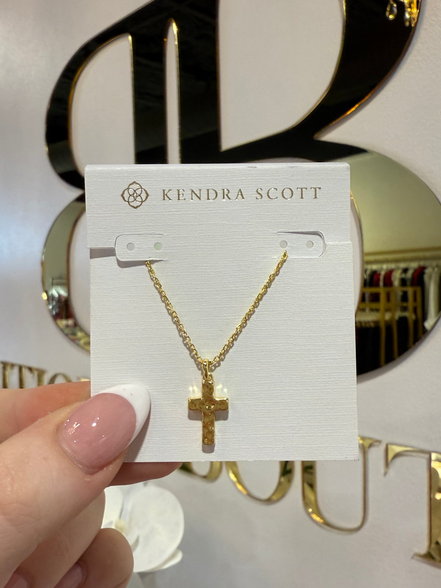 BOUTIQUE KENDRA SCOTT GOLD CROSS PENDANT NECKLACE IN HAND
