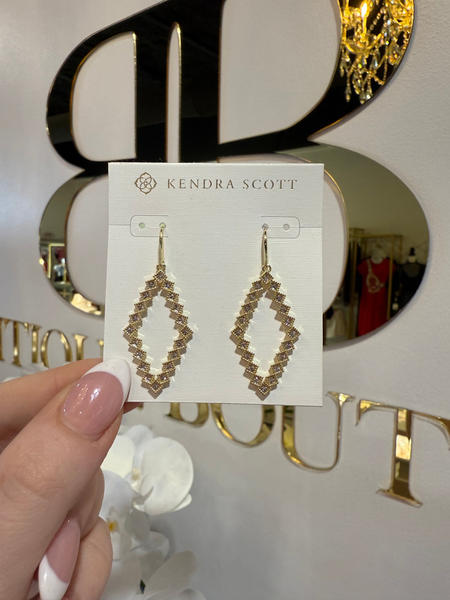 BOUTIQUE KENDRA SCOTT KINSLEY GOLD OPEN FRAME EARRINGS IN WHITE CRYSTAL IN HAND