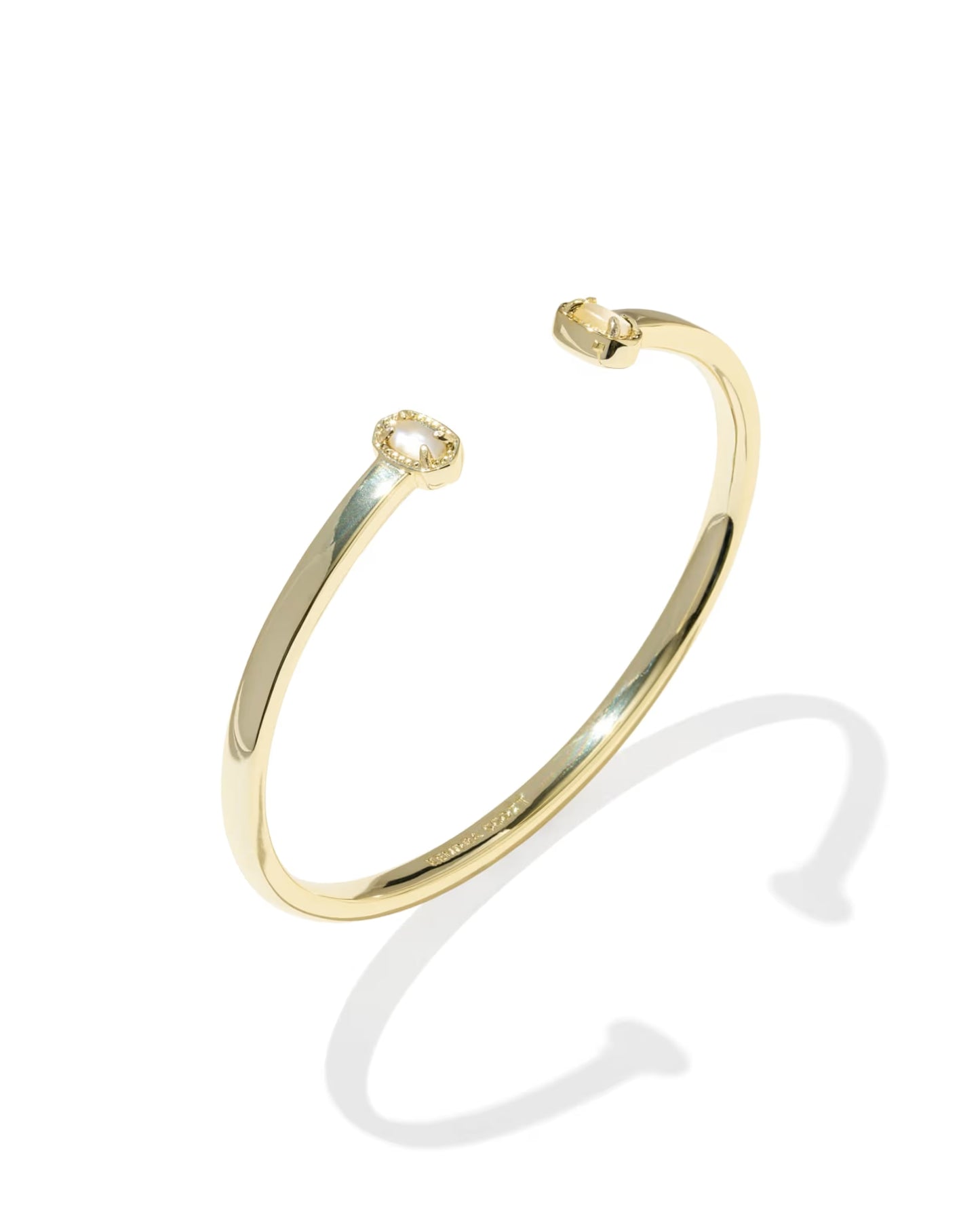 A polished yellow gold open cuff bangle bracelet with a small halo-style diamond setting on one end, shown on a clean white background with a soft shadow.