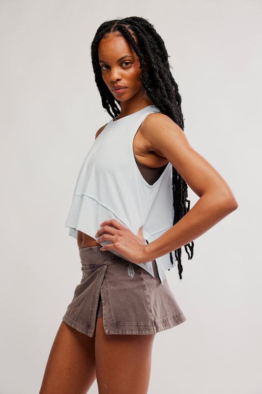 Woman wearing a light gray sleeveless top and brown shorts on a white background