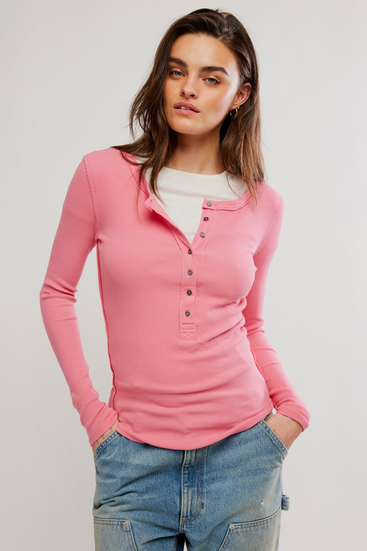 Woman wearing a pink long-sleeve shirt and blue jeans on a white background