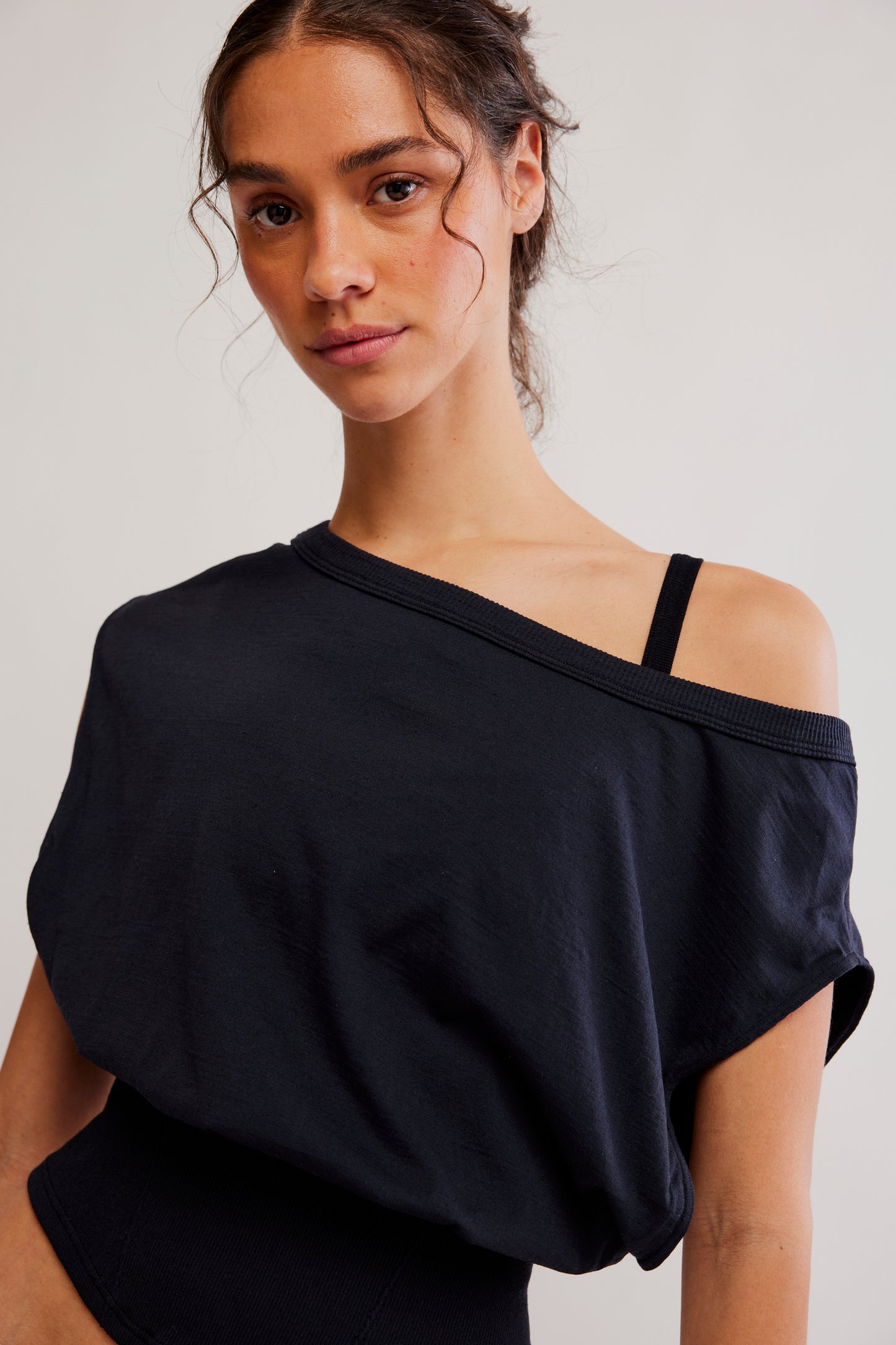 Woman wearing a black off-shoulder top against a plain background
